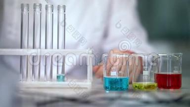 科学家在实验室玻璃器皿中处理液体。 试管灌装液